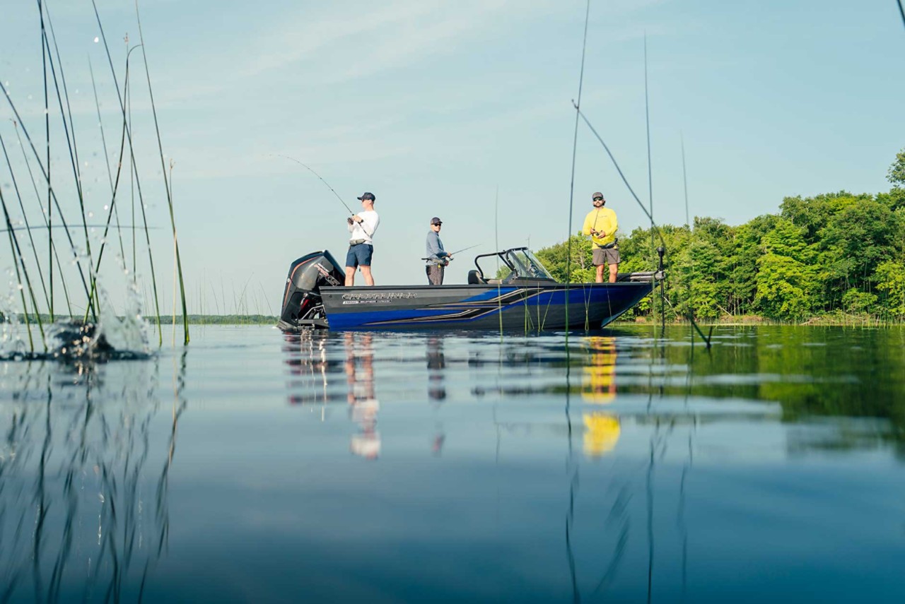 Three people fishing off their Crestliner boat on a lake.